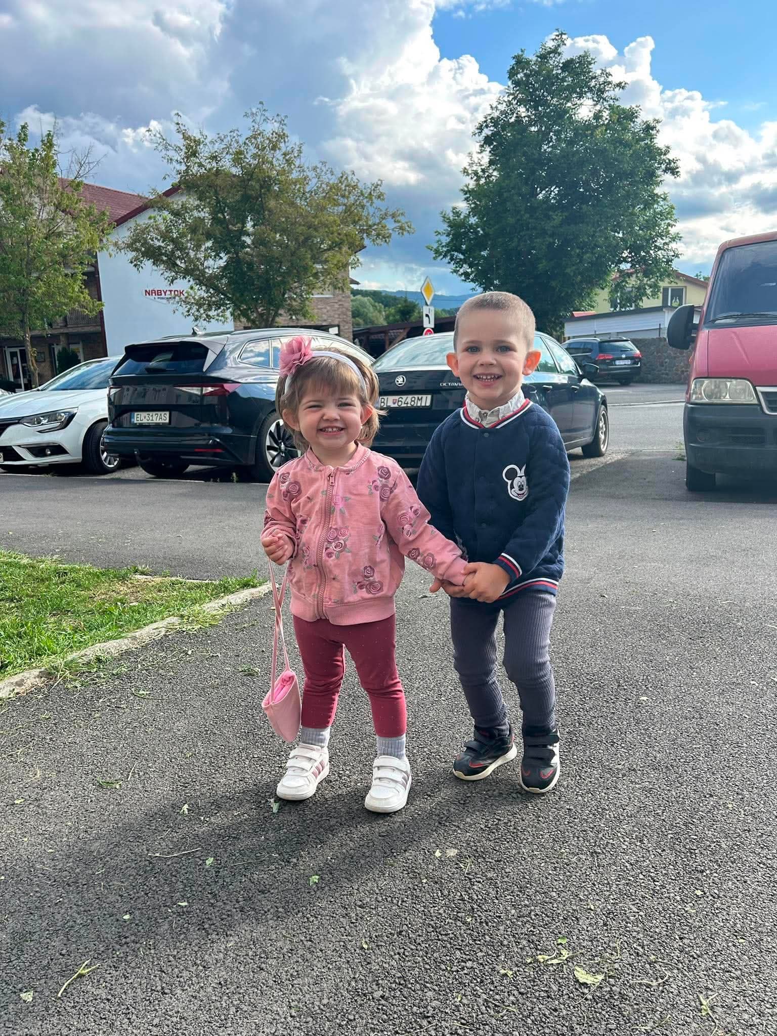 Pred úpravou: súrodenci držiaci sa za ruky na parkovisku